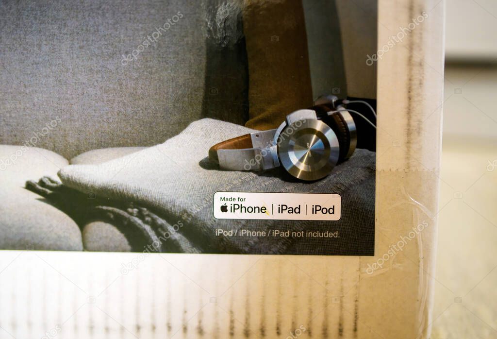 Paris, France- Feb 2, 2023: A section of a product box shows a pair of stylish over-ear headphones resting on a grey fabric surface with a sticker indicating compatibility with iPhone, iPad, and iPod devices