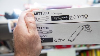 Paris, Fransa - 10 Mart 2025: Bir el iki IKEA ürün kutusunu, LED ve TRADFRI 'yi, elektrik, aydınlatma, aydınlatma, bağlantı ve kullanım simgeleri de dahil olmak üzere ayrıntılı özelliklerini göstererek tutar