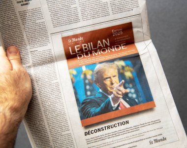 Paris, Fransa - 10 Mart 2025: Bir el Le Monde gazetesinin 2025 tarihli Le Bilan du Monde sayısında Donald Trump 'ın işaret ettiği bir kapağı ve 