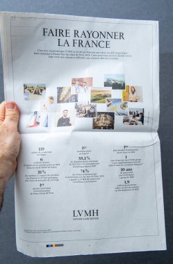 Paris, Fransa - 10 Mart 2025: Bir el, Faire Rayonner La France başlıklı tam sayfa LVMH gazetesi reklamını tutuyor, grupların başarılarını ve Paris 2024 Olimpiyatları 'nı görsel ve istatistiklerle destekliyor