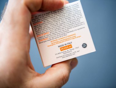 Paris, Fransa - 10 Mart 2025: Hulka Srl 'den alınmış krema kutusunu tutan kişinin yakın çekimi, ürün detaylarını İspanyolca, ISO 9001 sertifikası ve dermatolojik bilgileri gösteriyor