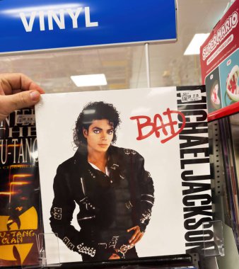 Berlin, Almanya - 12 Nisan 2025: Bir el, bir plak dükkanında, Wu-Tang Clan 'in yanındaki mavi tabelanın altında Michael Jackson Bad plağını tutuyor ve raflarda 