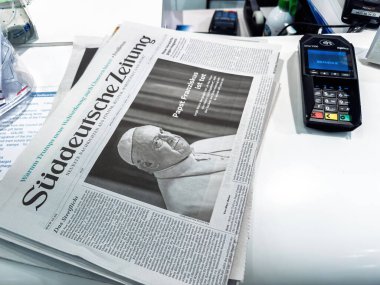 Paris, Fransa - 22 Nisan 2025: Papa Francis 'in ölüm ilanı manşetli Alman basını ödeme terminali yakınlarındaki bir büfe tezgahında ve satış noktasında çeşitli ürünler bulunuyor.