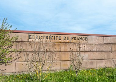 Strasbourg, Fransa - 30 Mart 2025: Fransa 'da Fransa' da bir EDF tesisinin sınırlarını belirleyen mavi gökyüzünün altında bulunan ve üzerinde Electricite de France yazıtları bulunan taş duvar