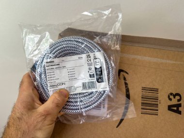 Paris, Fransa - 2 Nisan 2025: DeleyCON 'dan 10 metre örülmüş naylon kedi 7 ethernet yama kablosu, etiketli MK4562, beyaz bir duvara karşı Amazon A3 nakliye kutusunun üzerine yerleştirilmiş