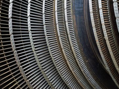 Elektrik jeneratörü veya endüstriyel motor montajının bir parçası olan kıvrımlı perçinlenmiş bıçaklar ve perçinlenmiş konnektörler içeren metalik türbin bileşenlerinin yakın çekimi