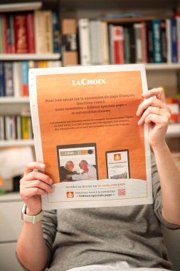 Paris, Fransa - 22 Nisan 2025: Bir kadın elinde La Croix gazetesi reklâm sayfasını tutarak Papa Francis 'in ardılı hakkında cesur turuncu tasarımı ve Vatikan görüntüleriyle abone olmaya davet ediyor.
