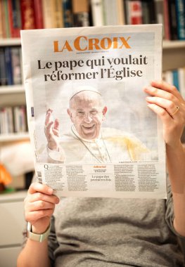 Paris, Fransa - 22 Nisan 2025: Gri kazaklı bir kadın La Croix gazetesinin ön sayfasında Papa Francis 'in kilisede reform yapma arzusuyla ilgili bir manşet yayınladı.