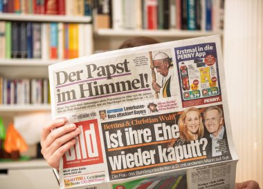 Paris, Fransa - 22 Nisan 2025: Bir kadın, Alman magazin gazetesi Bild 'in ön sayfasında Papa Francis' in vefatı ve Wulff 'ların evliliği hakkındaki spekülasyonların yer aldığı bir manşet okuyor.