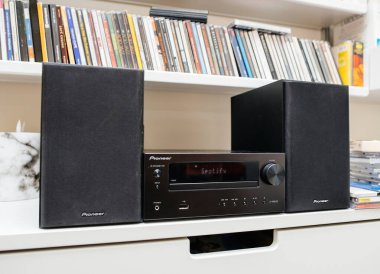 Paris, Fransa - 13 Mart 2023: Öncü stereo sistemi iki siyah hoparlör arasına yerleştirildi görünür Spotify ekran, kitaplarla dolu raflar ve kompakt disk yığınları ile çevrili.