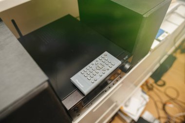 Paris, Fransa - 13 Mart 2023: Pioneer müzik seti sistemi ile uyumlu bir Pioneer uzaktan kumandası, beyaz bir rafta hoparlörler ve aksesuarlarla çevrili siyah ses ünitesinin tepesinde dinleniyor.