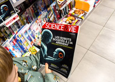 Paris, Fransa - 12 Mart 2025: Bir gazete bayiinde elinde Bilim ve Vie dergisi tutan genç bir çocuk, yapay zeka destekli robotların gelecekteki insan robotların yüz yüze olduğu bir kapak hikayesi.