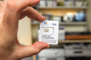 Paris, Fransa - 19 Nisan 2025: Bir kişinin Bouygues Telekom 5G SIM kartını bir ev ayarında taşınabilir bir değişiklik veya cihaz güncellemesi sırasında dikkatlice tutması