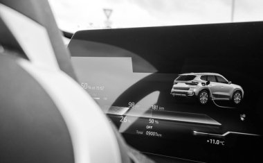 Dijital gösterge panelinin siyah ve beyaz yakın çekimleri modern bir araba kabininin içinde elektrikli araç aküsü durumunun ilerlemesini ve ısı ölçümünü gösteriyor.