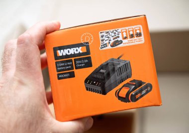 Paris, Fransa - 22 Nisan 2025: İçinde 20V 2.0V iyon pil ve PowerShare bahçe ve atölye aletleri için ideal lityum iyon pili bulunan turuncu Worx WA3601 kutusunu tutan elin yakın çekimi
