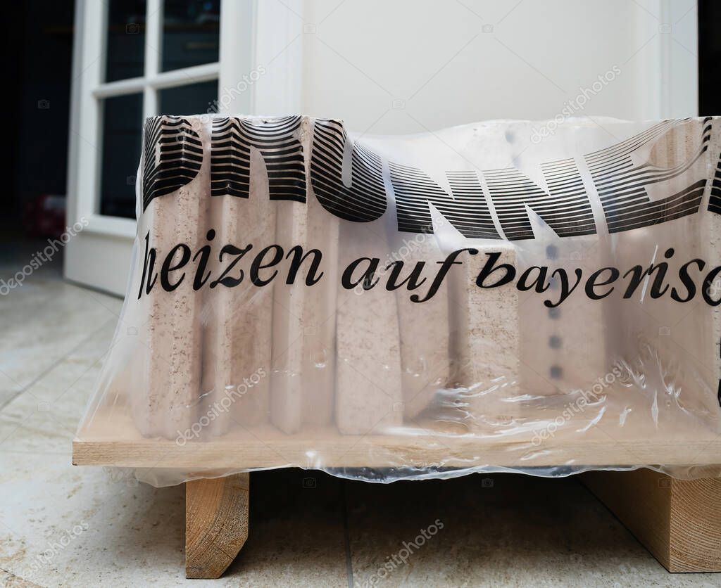 Munich, Germany - Apr 25, 2023: Fireclay bricks stacked on a wooden pallet covered with plastic wrap showing the Brunner logo and slogan Heizen auf bayerisch during a hall building installation for a wood burner.