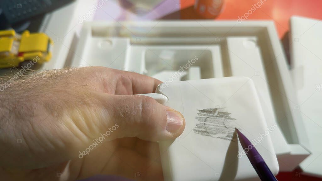 Paris, France - Apr 4, 2025: A person is using a pencil to shade over the surface of a new MacBook Pro M4 Max charger to reveal the faint Apple logo through pressure shading technique