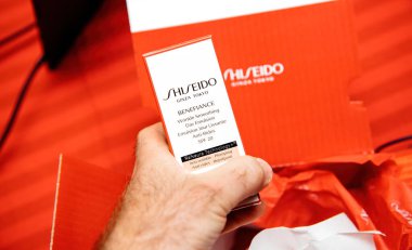 Paris, Fransa - 15 Nisan 2025: Bir kişi Shiseido Benefiance marka kırmızı ambalajlı, gösterişli lüks cilt sunumundan yeni açılmış, pürüzsüz bir gün emülsiyonu tutuyor