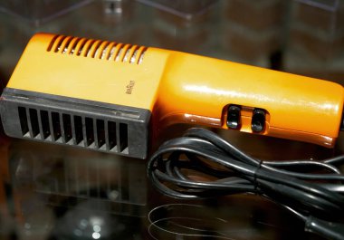 Paris, Fransa - 20 Nisan 2025: Minimalist dikdörtgen tasarımlı klasik turuncu Braun saç kurutma makinesi ve çift siyah şalterleri, Dieter Rams endüstriyel tasarım felsefesinin işlevsel estetiğini yansıtıyor.