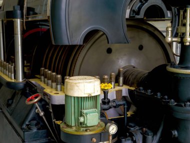 Paris, Fransa - 20 Nisan 2025: Yeşil bir elektrikli motor, büyük dönen diskler, hidrolik valfler ve bir güç üretimi veya makine dairesi içindeki basınç göstergesi içeren endüstriyel mekanik sistemin ayrıntılı görünümü