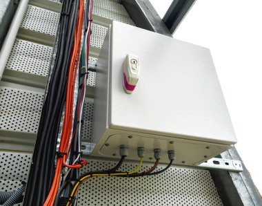 Etiketli kilit ve bağlı çok renkli kablolar ile monte edilmiş elektrik kontrol kutusu, delinmiş metal bir panele yerleştirilmiş kablolar ve merdiven benzeri bir kablo tepsisi