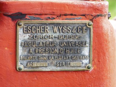 Paris, Fransa - 20 Nisan 2025: İsviçre, Zürih 'ten Escher Wyss ve Cie' nin pirinç teşhis plaketi, kırmızı bir endüstriyel makineye monte edilerek, çoğu ülkede patentli evrensel bir yağ-basınç düzenleyici olarak etiketlendi.