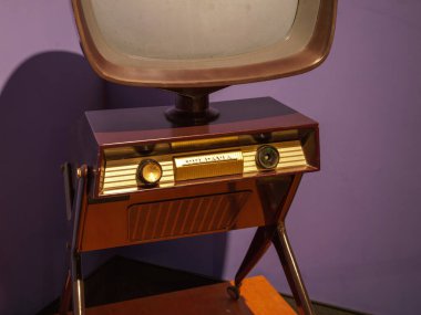 Paris, Fransa - 20 Nisan 2025: Eğri ekran ve retro kontrol paneli olan klasik televizyon seti, orta-yüzyıl modern tasarımı ve tripod tarzı metal bacaklara sahip mor bir duvara karşı sergileniyor