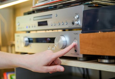 PAris, Fransa - 22 Nisan 2025: Bir kişi gümüş bir Onkyo önamplifikatör P-3000R üzerindeki doğrudan düğmeye basıyor, eşleşen bir Super Audio CD oynatıcısının altında yüksek-kurgu ses kayıt cihazıyla donatılmış