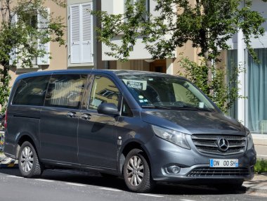 Paris, Fransa - 30 Nisan 2025: Gri Mercedes-Benz minibüs etiketli Cenaze Merasimi Fransa 'da bir iskan caddesine park edilmiş, camlarında binalar ve yakındaki yeşil ağaçların yansımaları var
