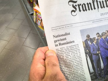 Frankfurt, Almanya - 6 Mayıs 2025: Bir kişi Romanya 'da iyi aydınlatılmış bir dergi koridorunda görülebilen ön sayfa milliyetçiliğine sahip bir gazeteyi elinde tutuyor