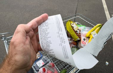 Frankfurt, Almanya - 6 Mayıs 2025: Bir tüketici, dolu bir market arabasının yanında toplam 92,30 avroluk bir makbuz ve tüketici maliyetlerini ve gıda fiyat enflasyonunu ön plana çıkaran dolu bir bagaja sahip.