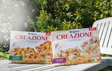 Paris, Fransa - 17 Mayıs 2025: İki Wagner Creazione pizza kutusu, Akdeniz ve İncirli Keçi Peyniri aromalı, açık hava masasında yan yana, yemyeşil bir arka planda, yemyeşil,