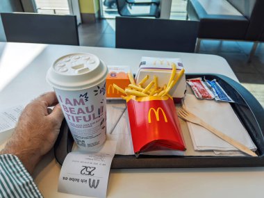 Berlin, Almanya - Bölüm 14, 2023: Bir el McDonald tepsisinde patates kızartması, içecek bardağı, tavuk nugget ve soslarla dinleniyor..