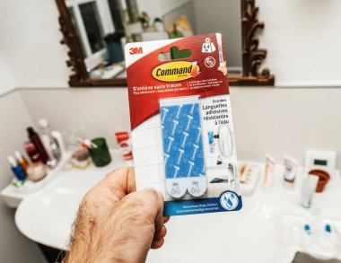 Paris, Fransa - 22 Nisan 2025: Banyoda çeşitli tuvalet malzemeleri ve arka planda bir ayna bulunan büyük su geçirmez bantlardan oluşan 3M komut paketi,.