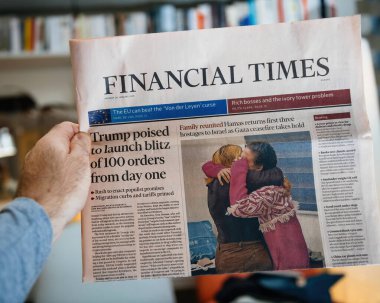 Paris, Fransa - 21 Ocak 2025: Bir kişi Financial Times gazetesinin ön sayfasında Trump 'ın icra emirleri baskını ve aile birleşme fotoğrafı planladığına dair cesur bir manşet yayınladı