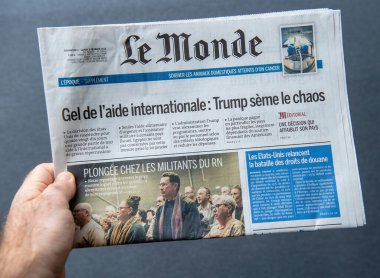 Paris, Fransa - Mar 13, 2025: Le Monde gazetesini elinde tutan ve Trump 'ın uluslararası yardımların dondurulması ve küresel istikrarsızlığın artması hakkında manşet atan kişinin yakın çekimi.