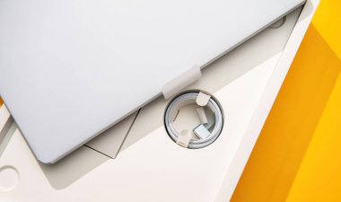 Paris, Fransa - 13 Mart 2025: MacBook Air M4 'ün beyaz ambalajından kaldırdığı mat gümüş rengi MacBook Air M4, sarmalanmış bir USB-C kablosunu stüdyo ışıklandırması altında dizüstü bilgisayarın yanındaki özel dairesel bir bölmede ortaya çıkarıyor.