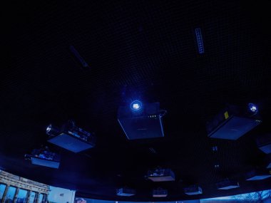 Paris, Fransa - 5 Nisan 2025: Koyu renk desenli bir şebeke, uzayda asılı duran ve parlak mavi ışık yayan çoklu siyah projektörleri destekler ve modern bir galeride büyüleyici bir görüntü oluşturur