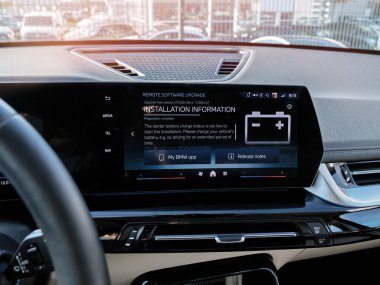 Paris, Fransa - 27 Mart 2025: Bir BMW iX1 gösterge panelinin iç görünümü uzaktan yazılım güncelleme bilgileri, pil şarj uyarısı, navigasyon menüsü ve kontrol simgeleri ile merkezi bilgi ekranını gösteriyor.