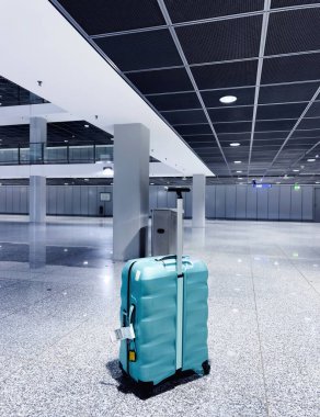 Turkuaz sert kabuklu bavul Frankfurt Havalimanı 'nın cilalı zemininde duruyor..