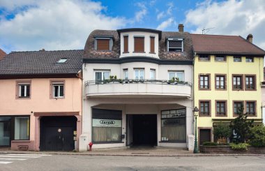 Wasselone, Fransa - 9 Haziran 2025: Kavisli balkonlu eski ticari bina, kapalı mağaza pencereleri ve Wasselonne, Alsace 'deki apartmanlar