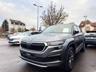 Paris, Fransa - 6 Aralık 2023: Skoda Kodiaq, arka planda nemli koşulları yansıtan çevre otomobiller ve banliyö binalarıyla yağmurlu galeriye park etti.