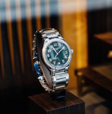 Palma, İspanya - 15 Temmuz 2025: Yeşil düğmeye yakın çekim Patek Philippe saat elmas bezel ve bilezik, sıcak ışıklandırma ve ahşap sunum butikte sergilenmektedir.