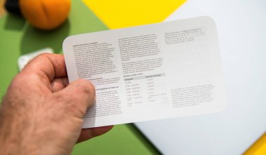 Paris, Fransa - 13 Mart 2025: Bir el, renkli yeşil ve sarı arkaplan üzerinden ürün özellikleri ve kablosuz frekans ayrıntılarını gösteren Hollandaca yazılmış bir Apple broşürü tutuyor