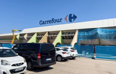 Sa Coma, İspanya - 16 Temmuz 2025: Sa Coma, Mallorca 'daki Carrefour süpermarketinin dışı, açık mavi bir gökyüzü altında park edilmiş arabaları ve yenileme çalışmaları ile