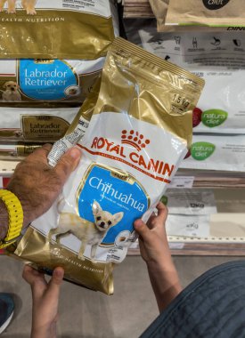 Inca, İspanya - 17 Temmuz 2025: Çocuk ve yetişkin, Mallorca 'da bir evcil hayvan reyonunda Chihuahua cinsi için bir Royal Canin Puppy yemek poşeti tutuyor