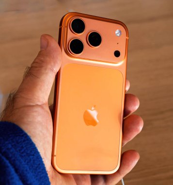 Paris, Fransa - Sep 19, 2025: Apple iPhone 17 Pro Max akıllı telefon canlı turuncu renkli, Apple Store 'da bir erkeğin elinde üçlü kamera sistemi ve premium modern tasarımı gösteriyor