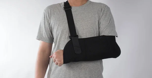 Broken arm. Arm Sling therapy support and covered around elbow first knuckle broken arm. Post Operative Care. Fractures of humerus radius ulna scapula. Arm Sling after accident. Isolated background.