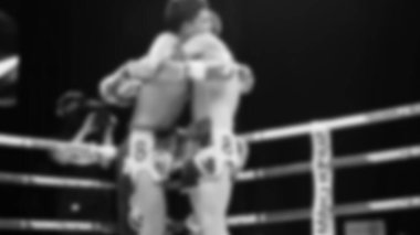 Blurred images black and white photo style of Thai boxing or Muay Thai or Kickboxing which local and foriegn boxer are fighting on the ring at indoor stage as martial art sport. Muay Thai Kick boxing