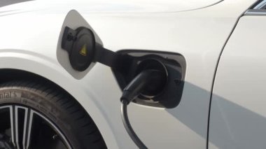 EV vagonu yükleniyor. Araba parkında EV şarj aletini kullanarak hızlı şarj etmek ki bu da gelecekteki ulaşım enerji teknolojisi demek. EV Charger araba istasyonu şarj oluyor. Elektrik motoru için AC veya DC soket prizi kullanın..